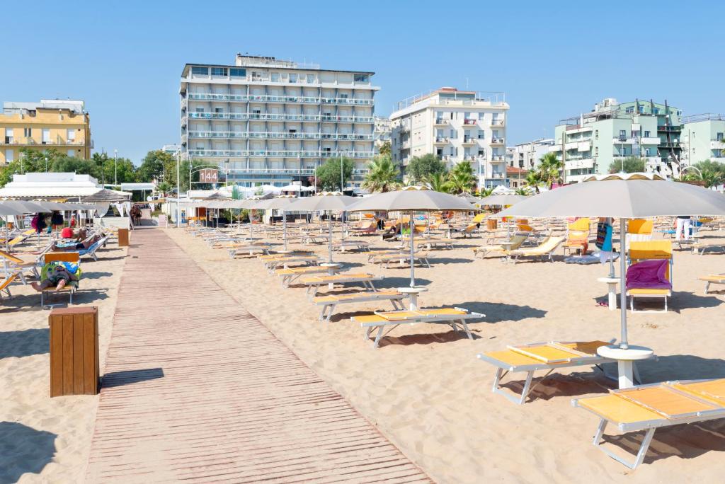uma praia arenosa com espreguiçadeiras e guarda-sóis em Hotel Centrale Miramare em Rimini