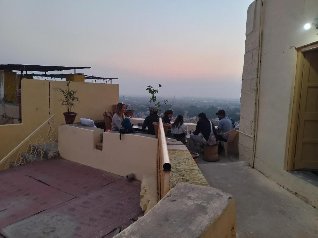 eine Gruppe von Menschen, die auf dem Felsvorsprung eines Gebäudes sitzen in der Unterkunft Hostel Magic Home Stay jaisalmer in Jaisalmer