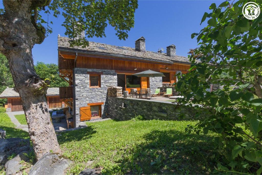 an exterior view of a stone house with a yard at Chalet Duhoux in Les Allues