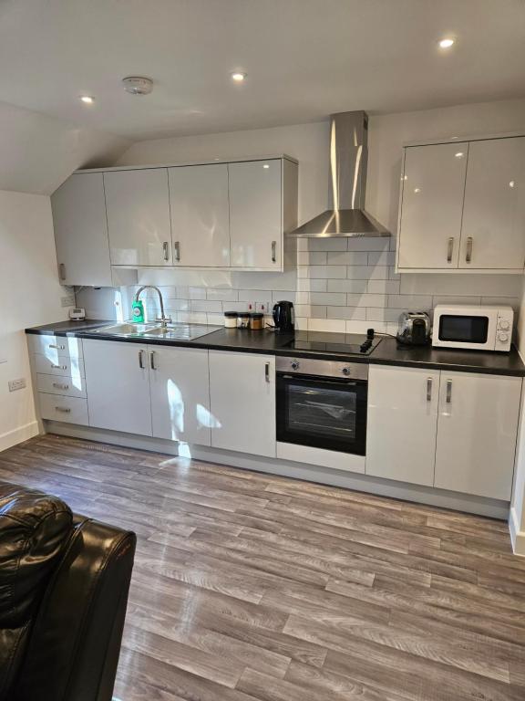 a kitchen with white cabinets and a stove top oven at Quiet Hideout in Southend-on-Sea