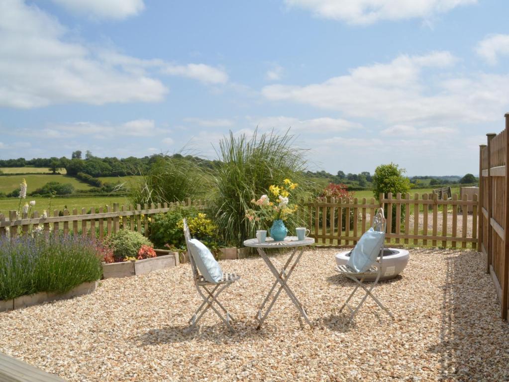 South Cadburyにある1 bed property in Sherborne 86426のフェンス付きの庭園内の椅子2脚とテーブル