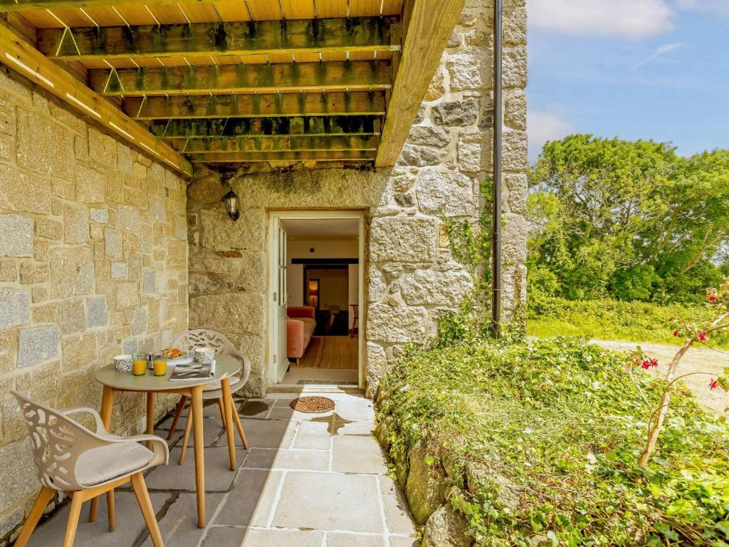 un edificio de piedra con una mesa y sillas en un patio en 1 Bed in Marazion 88008, en Ludgvan