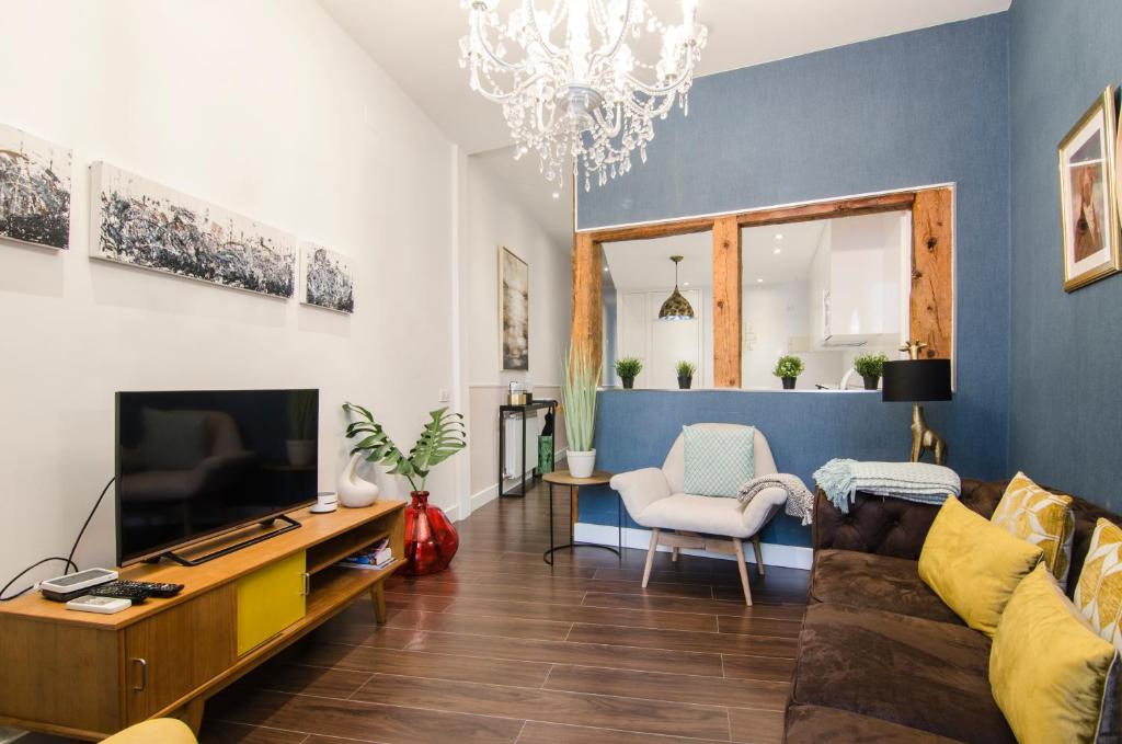 ein Wohnzimmer mit einem Sofa und einem TV in der Unterkunft APARTAMENTO EN SANTA ANA - SOL (2H + 2B) in Madrid