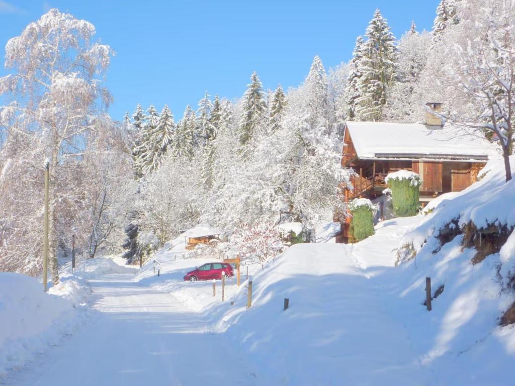 a house covered in snow with a red car at Chalet de Marie proche des Saisies in Queige