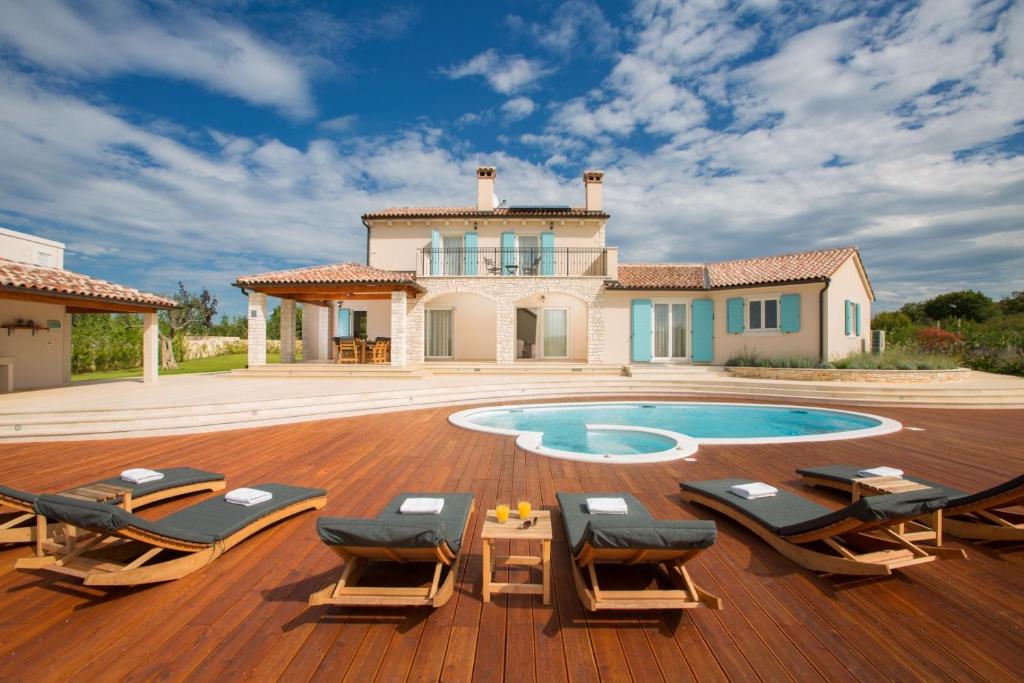 a house with a swimming pool and a deck with lounge chairs at Villa Aurora near Rovinj for 8 persons with sea view & whirlpool in Bale