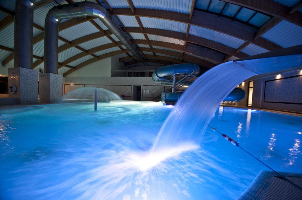 a swimming pool with a water slide in a building at Hotel Venus in Kolbudy