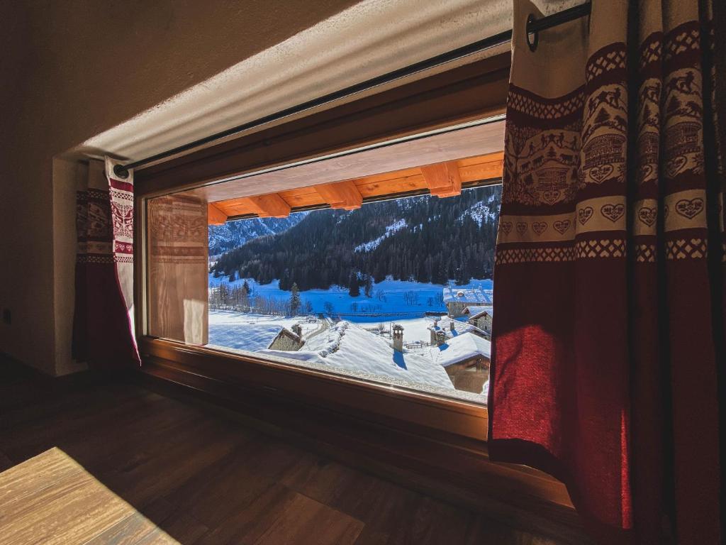 una ventana en una habitación con vistas a una montaña nevada en Aux Pieds du Malatra' 1, en Saint-Rhémy-en-Bosses