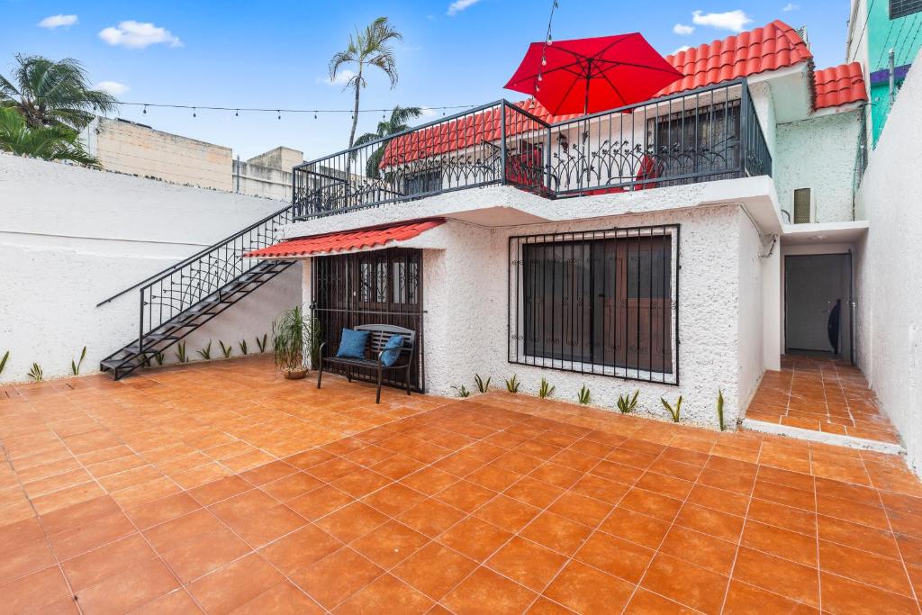 a house with a balcony with a red umbrella at Casa Nance Alojamientos GRAN MAYA Centro Mercado 28 y ADO Doble Suite Familiar 7 Personas in Cancún