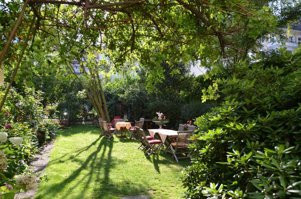 a garden with a table and chairs under a tree at Das Literaturhotel Berlin in Berlin