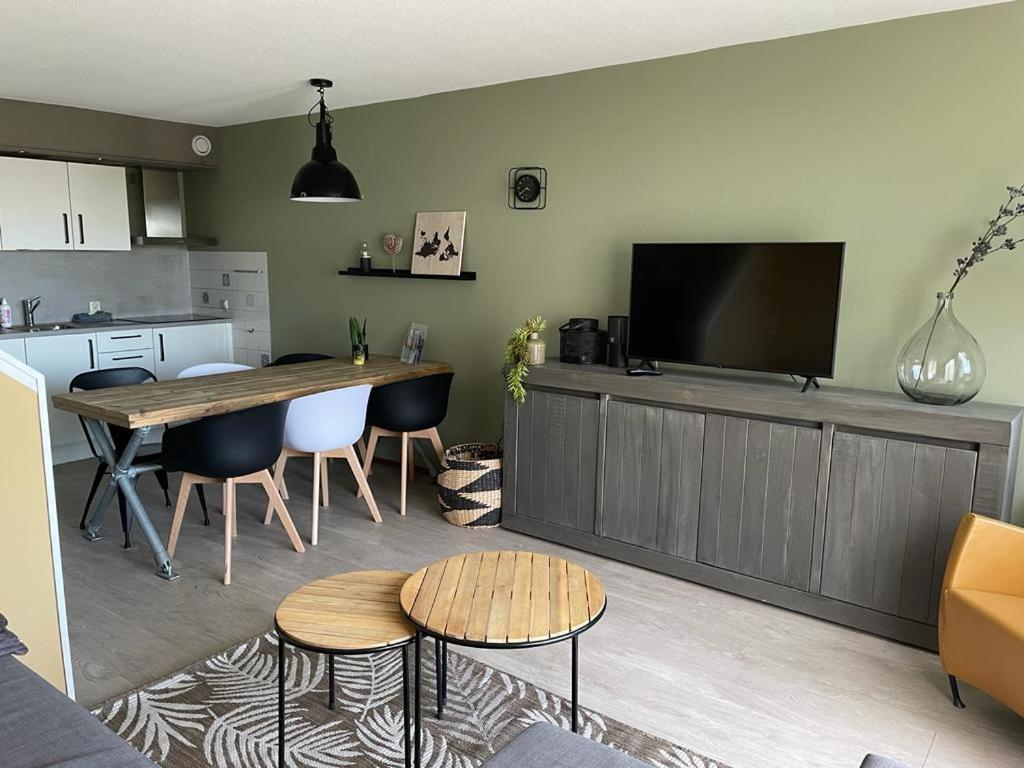 een woonkamer met een tafel en een keuken met een tv bij Appartement Senang, Resort Amelander Kaap in Hollum