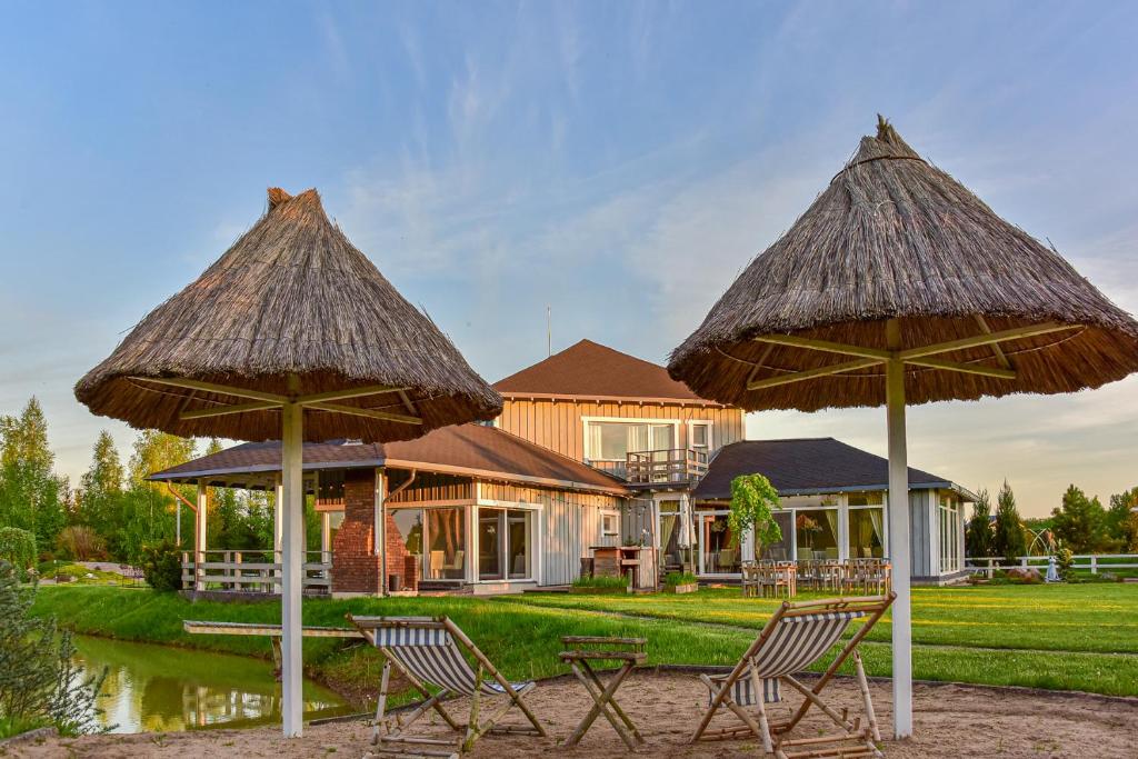 two chairs and umbrellas in front of a house at Vila 9Vėjai in Girininkai