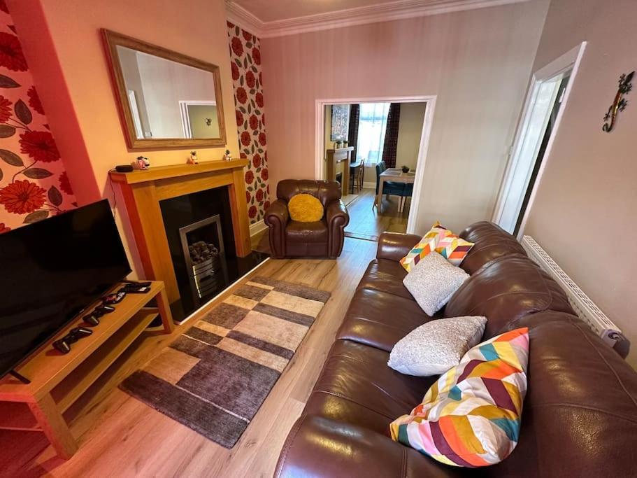 a living room with a leather couch and a fireplace at Modern 3BD Home Doncaster South Yorkshire in Doncaster