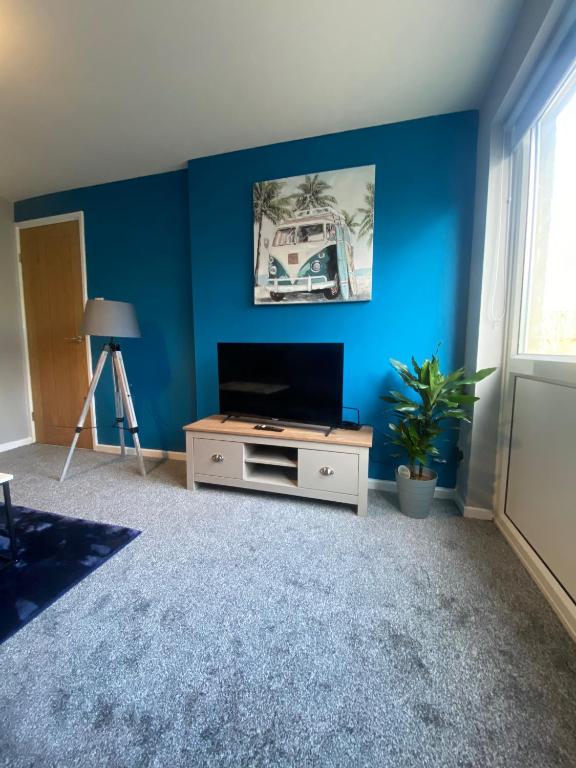 a living room with a tv and a blue wall at Modern Home with Free Parking Sleeps 6 in Leeds