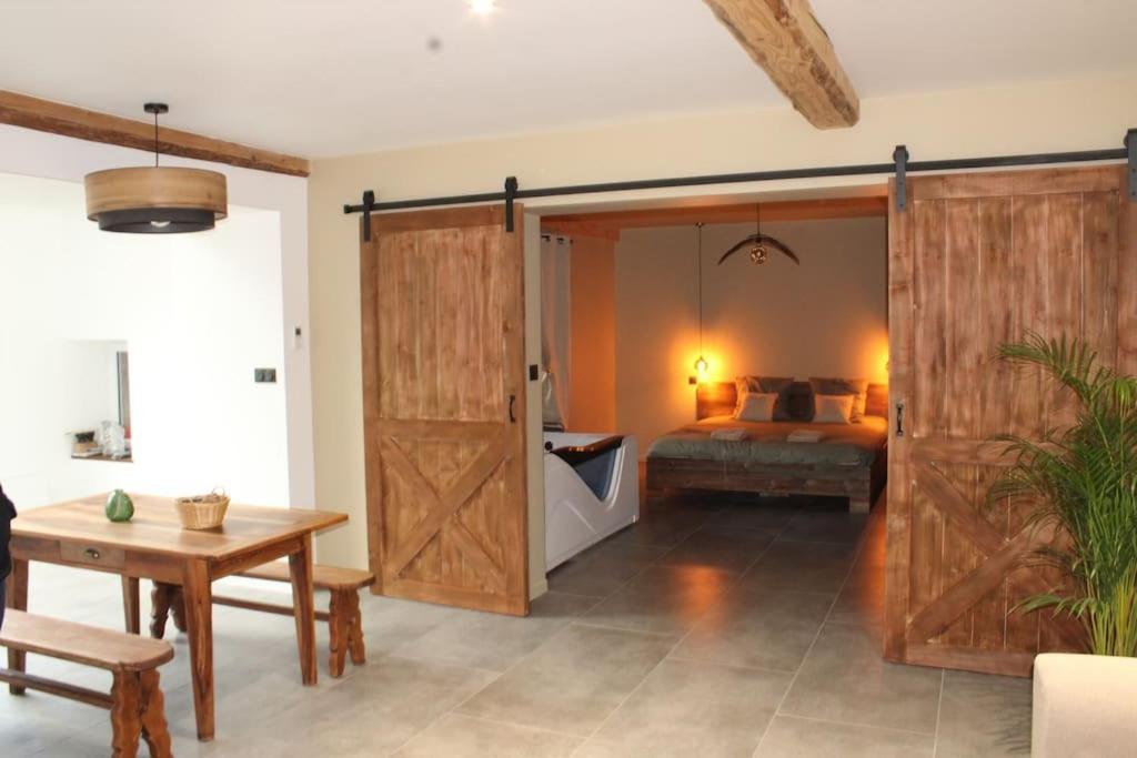 a bedroom with a bed and a wooden sliding door at Superbe appartement avec jacuzzi et jardin privé in Marlhes