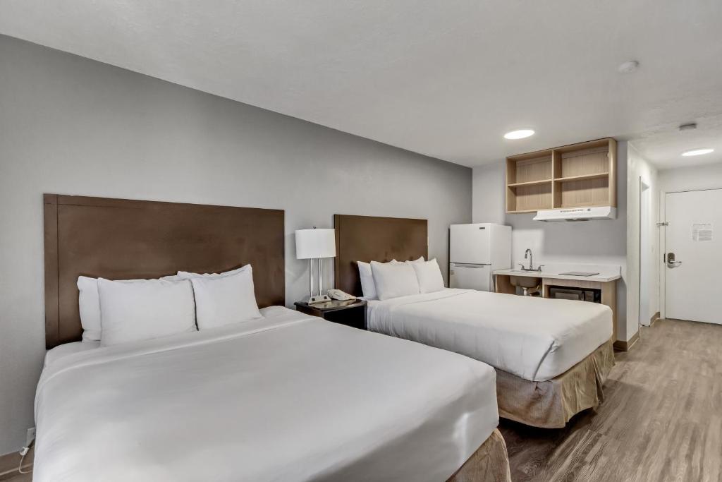a hotel room with two beds and a kitchen at Suburban Studios Salt Lake City Airport in Salt Lake City