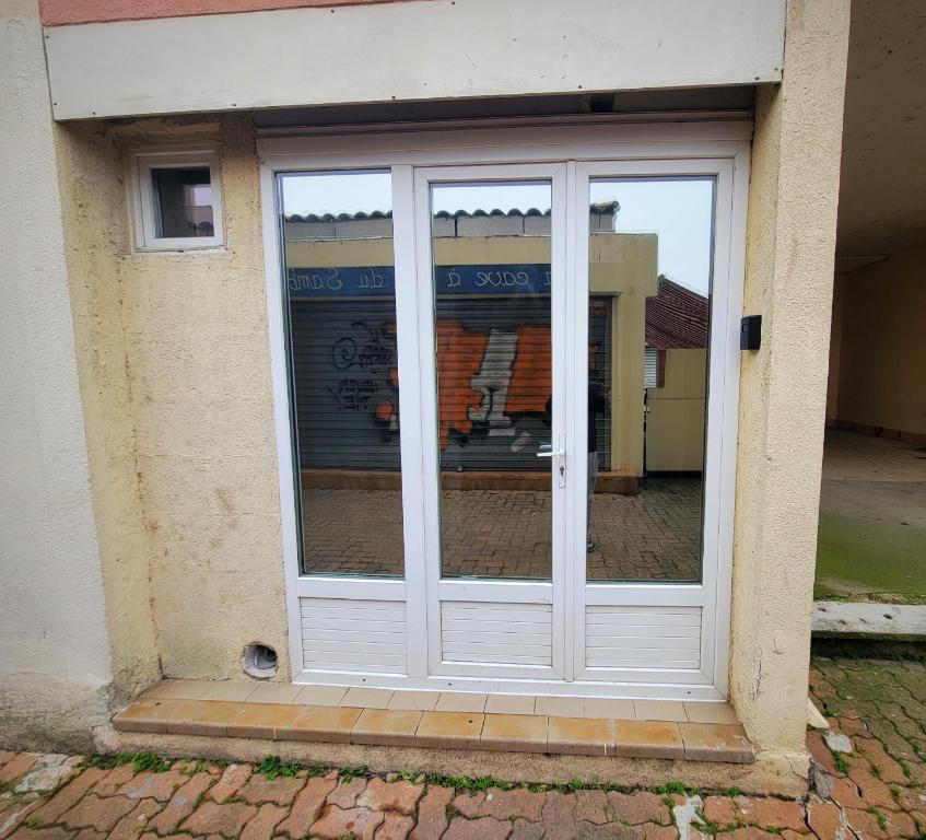 a sliding glass door with a reflection of a building at Studio 1 piece vacances proche de la mer in Le Grau-du-Roi