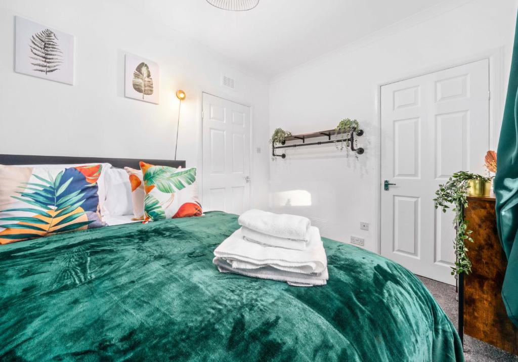 a bedroom with a green bed with towels on it at Uddingston Apartment by Klass Living in Uddingston