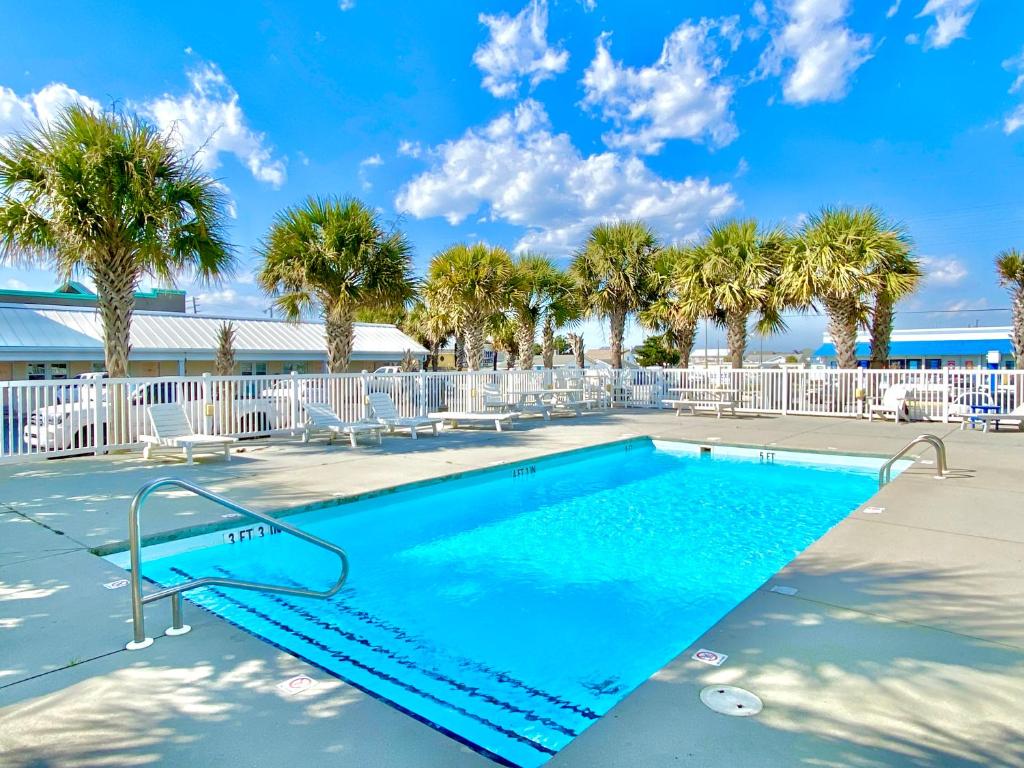 a swimming pool at a resort with palm trees at Island Inn of Atlantic Beach in Atlantic Beach