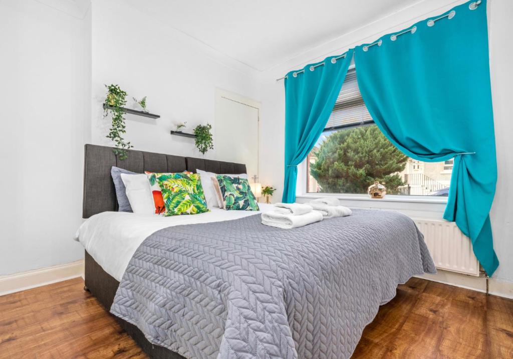 - une chambre avec un lit doté de rideaux bleus et d'une fenêtre dans l'établissement Nicol Apartment by Klass Living Airdrie, à Airdrie