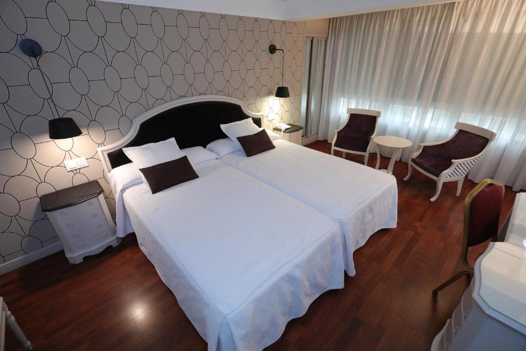 ブルゴスにあるHotel Corona de Castilla Burgosのベッドルーム1室(大型ベッド1台、テーブル、椅子付)