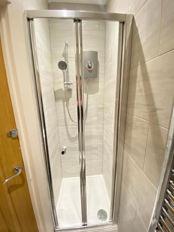 y baño con ducha y puerta de cristal. en En-suite near Stratford in a guesthouse, en Londres