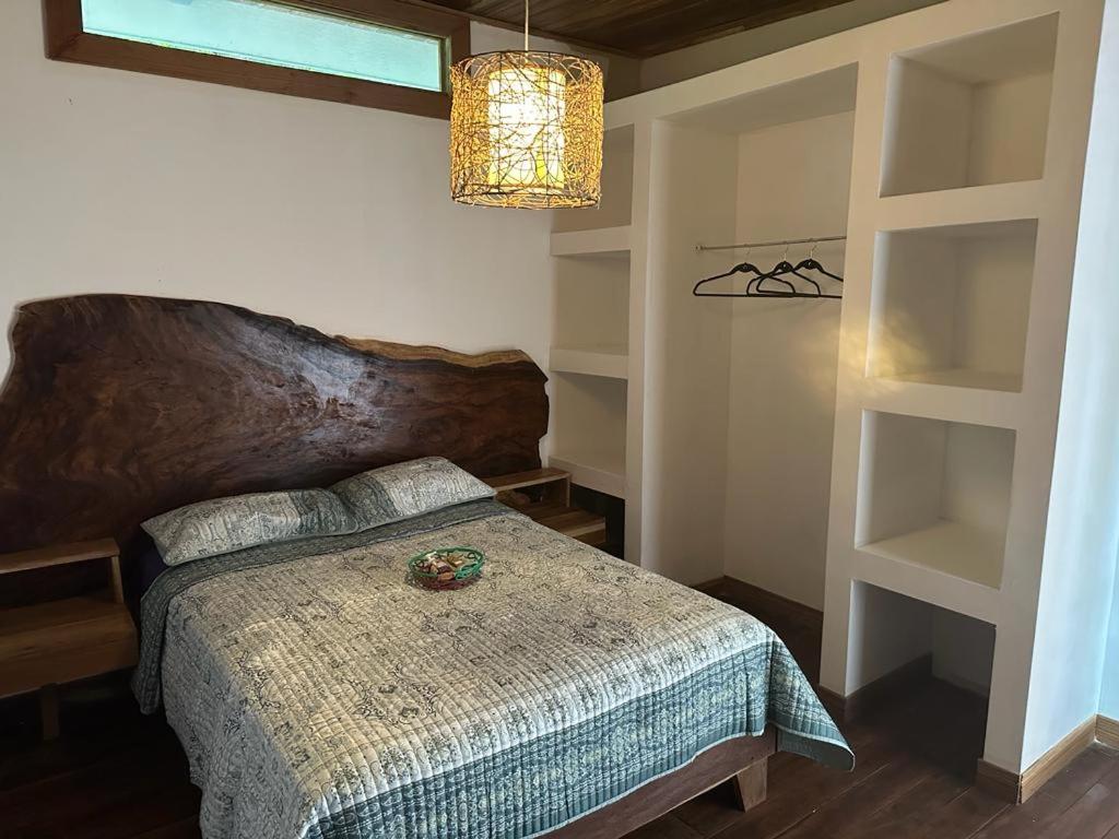 1 dormitorio con 1 cama con cabecero de madera y estanterías en Casita Flor de Loto, en Puerto Viejo