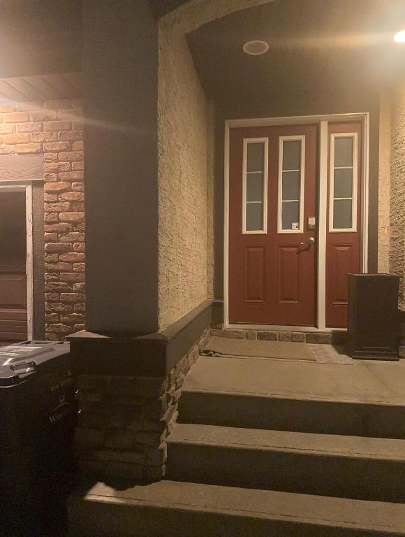 a front door of a building at night with stairs at Comfortable 3 Bed Basement Unit in Winnipeg