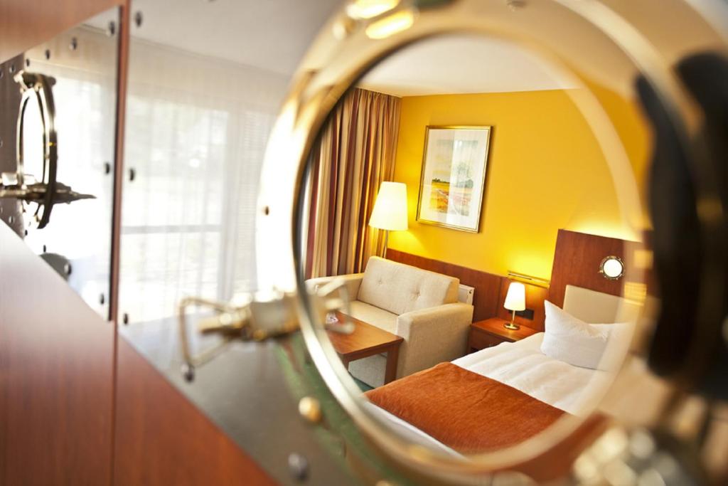 ein Hotelzimmer mit einem Bett und einem Spiegel in der Unterkunft SEETELHOTEL Nautic Usedom Hotel & Spa in Ostseebad Koserow