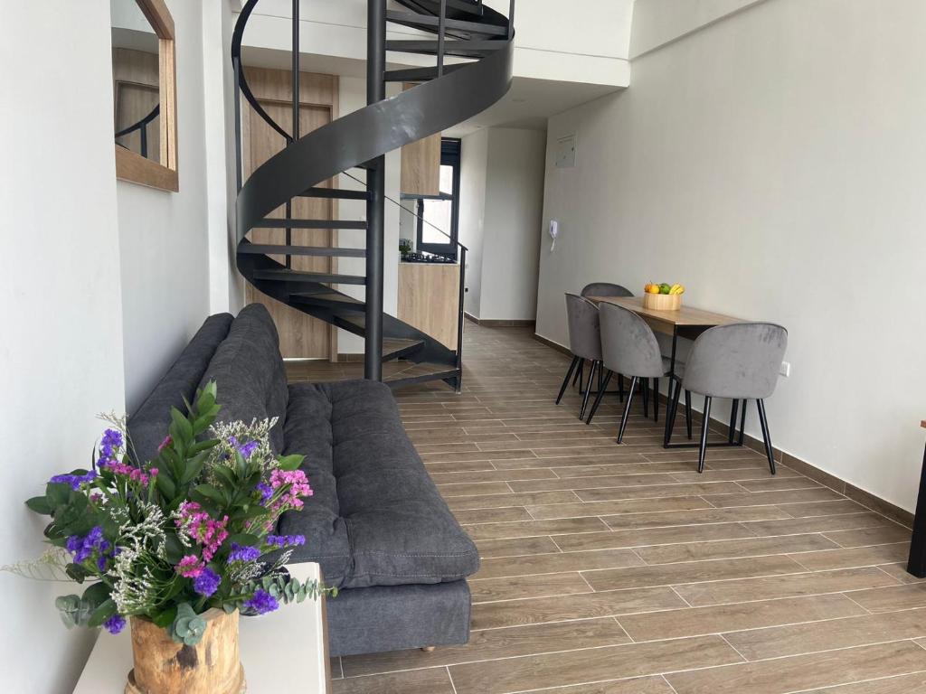 ein Wohnzimmer mit einem Sofa und einem Tisch mit lila Blumen in der Unterkunft Moderno dúplex tipo loft 1BR in Cartagena de Indias