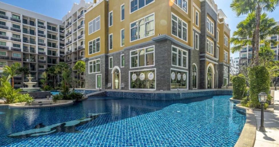 a building with a swimming pool in front of a building at Arcadia Beach Continental by Saowanee in Pattaya South