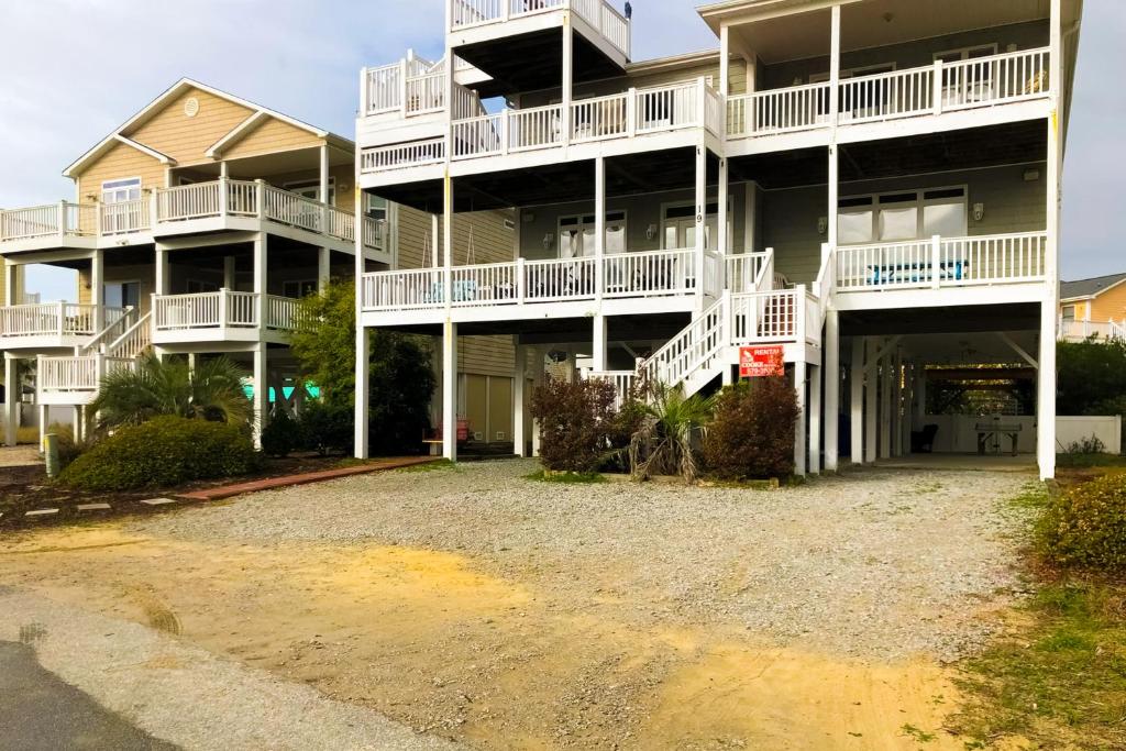 un gran edificio de apartamentos con balcones blancos y aparcamiento en All Decked Out en Ocean Isle Beach