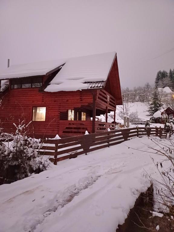 a log cabin in the snow with a fence at Deea Cascada in Vidra
