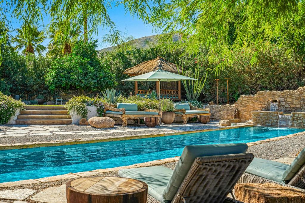 a swimming pool with chairs and a gazebo next to a swimming pool at Hacienda Hideaway in Rancho Mirage