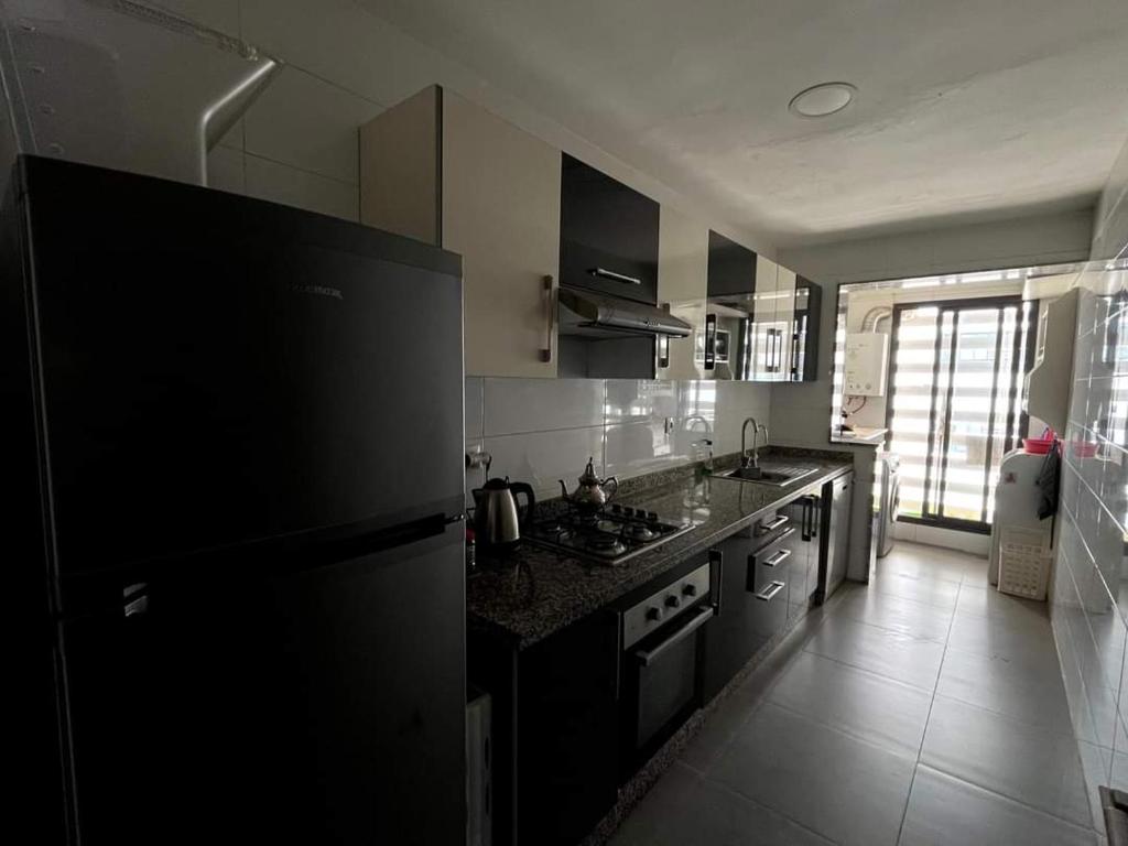 La cuisine est équipée d'un réfrigérateur noir et d'un évier. dans l'établissement Appartemment 3 pièces à Harhoura, à Harhoura