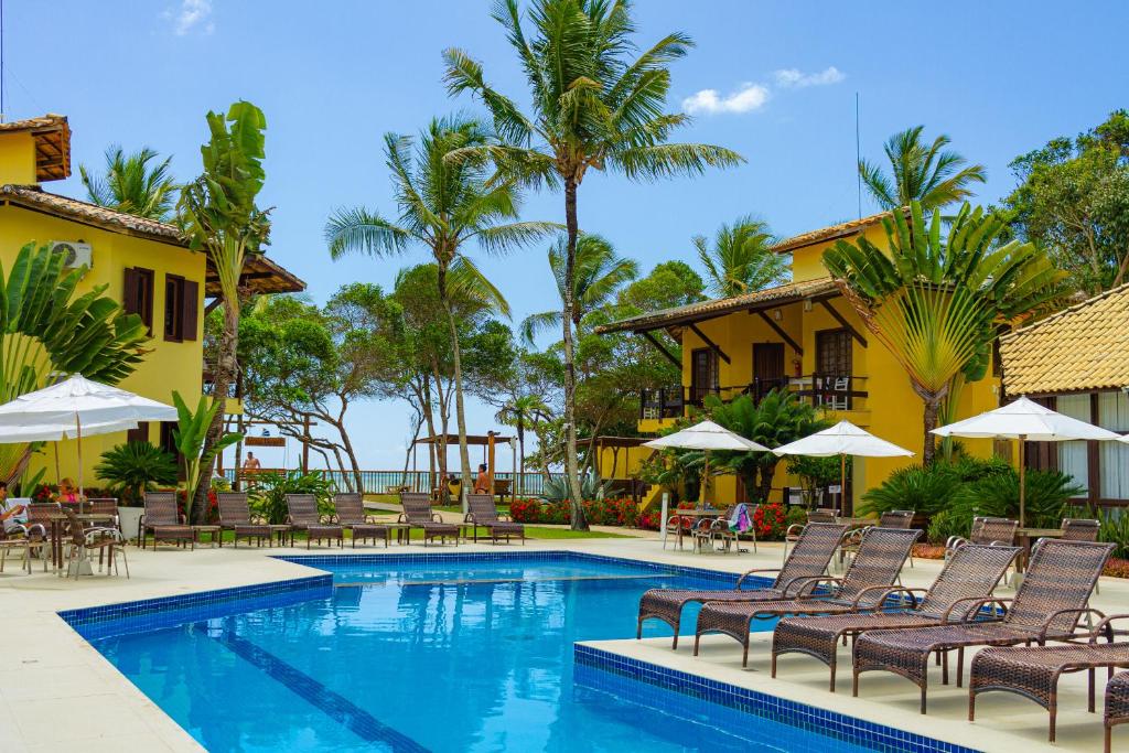 un complejo con piscina con sillas y sombrillas en Arraial Bangalô Praia Hotel en Arraial d'Ajuda