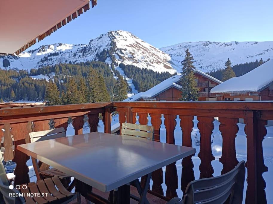 una mesa y sillas en un balcón con una montaña nevada en Studio au pied des pistes avec vue sur la montagne, en Mieussy