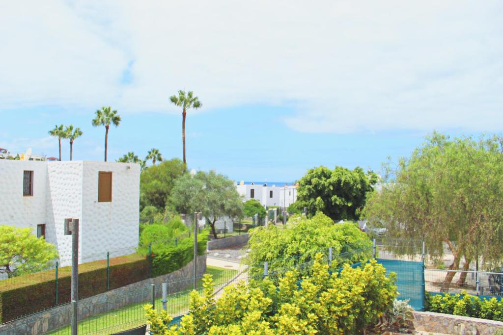 een uitzicht op een gebouw met bomen en een hek bij Playa Troya In front of Beach, Very quiet in Playa de las Americas