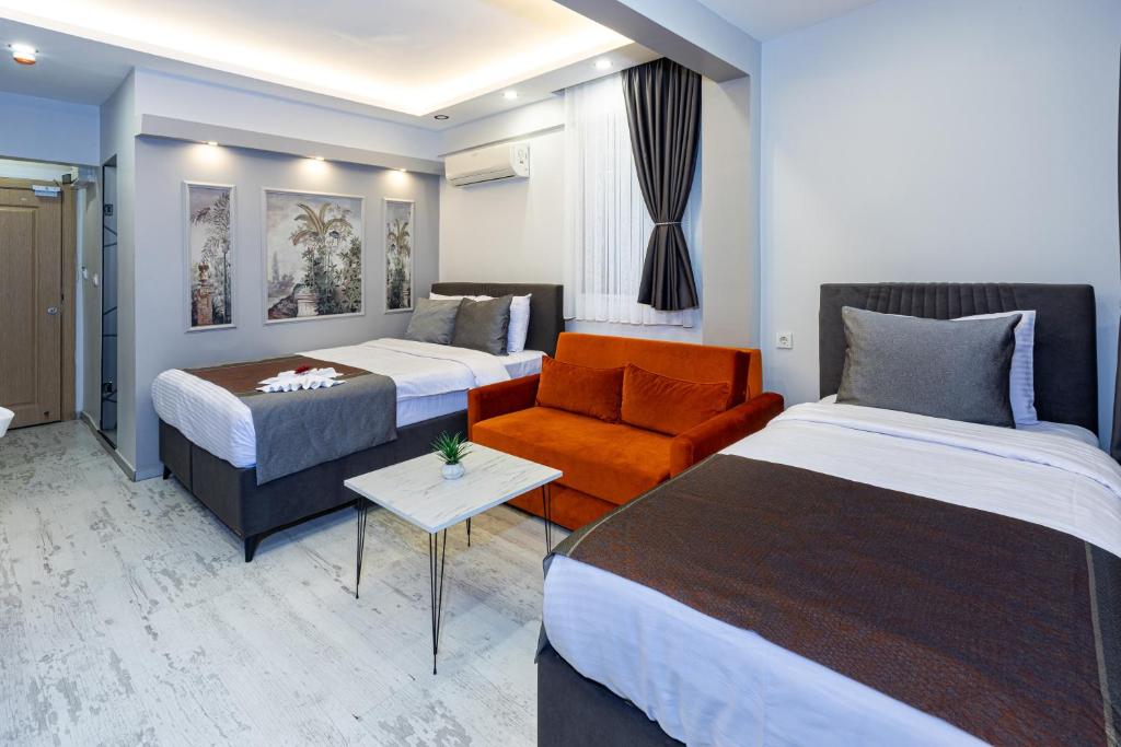 イスタンブールにあるAPOLLO HOTEL & APARTMENtSのベッド2台とソファが備わるホテルルームです。