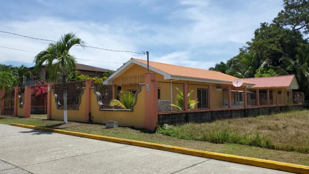 uma pequena casa amarela ao lado de uma rua em Casa en la playa puerto cortes em Puerto Cortes