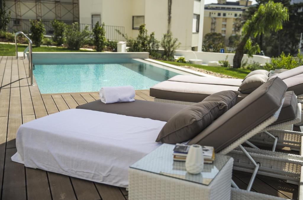 a group of beds sitting next to a swimming pool at Somewhere - Estoril Guesthouse in Estoril