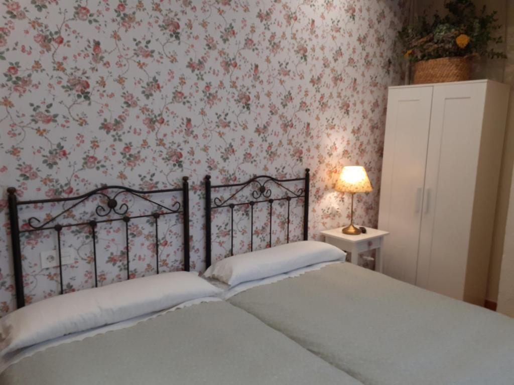 um quarto com uma cama com papel de parede floral em Uría 25 rooms em Oviedo