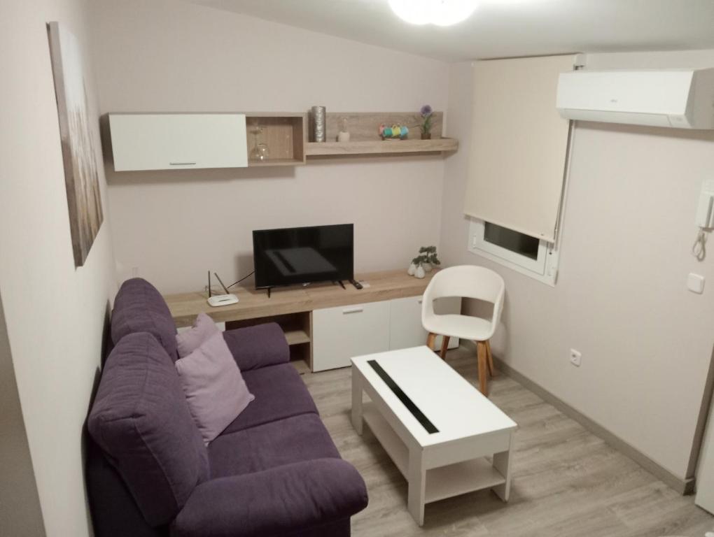 - un salon avec un canapé violet et un bureau dans l'établissement Apartamento la Soledad, junto al Alcázar, à Tolède