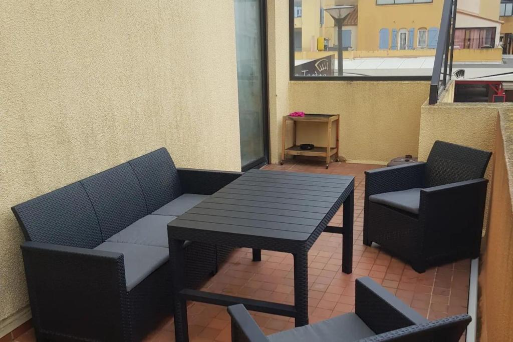 een patio met een tafel en stoelen en een tafel en stoelen bij pleasant cocoon just a stone's throw from the sea in Le Barcarès