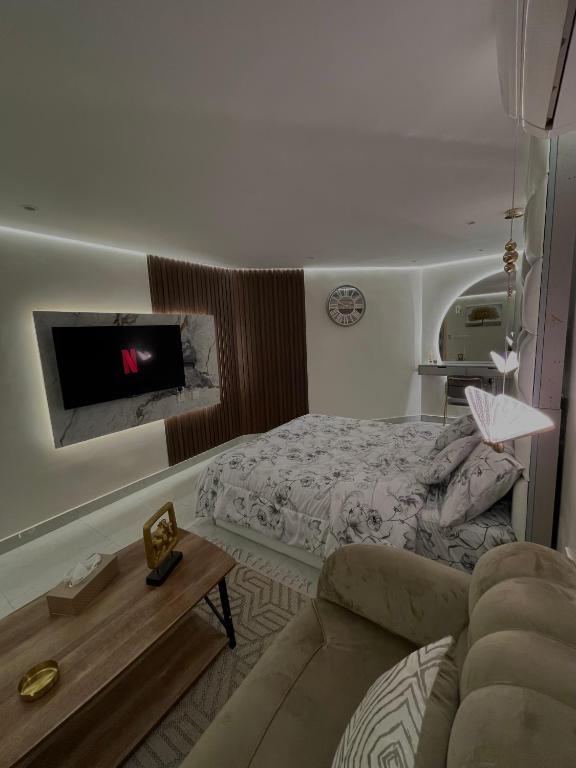 a bedroom with a bed and a couch and a tv at استديو مع جلسة خارجية بدخول ذكي in Riyadh