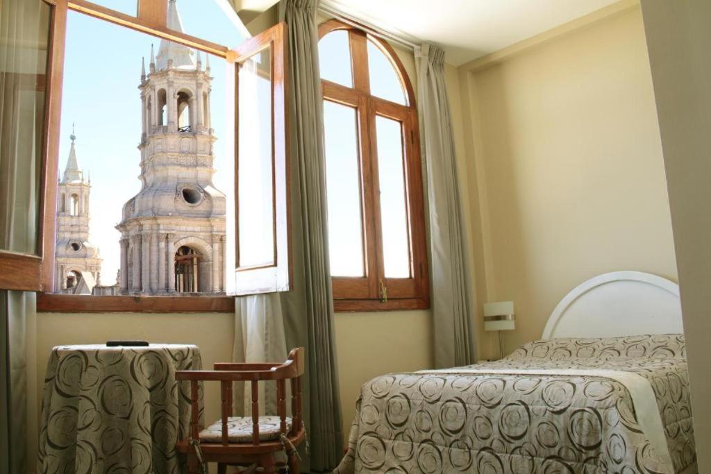 een slaapkamer met een bed en een raam met een toren bij Arequipa Suite Plaza Hotel in Arequipa