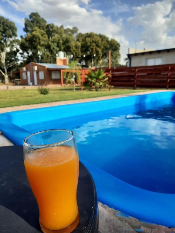 una copa de zumo de naranja en una mesa junto a la piscina en Lo de Lito en Sierra de la Ventana