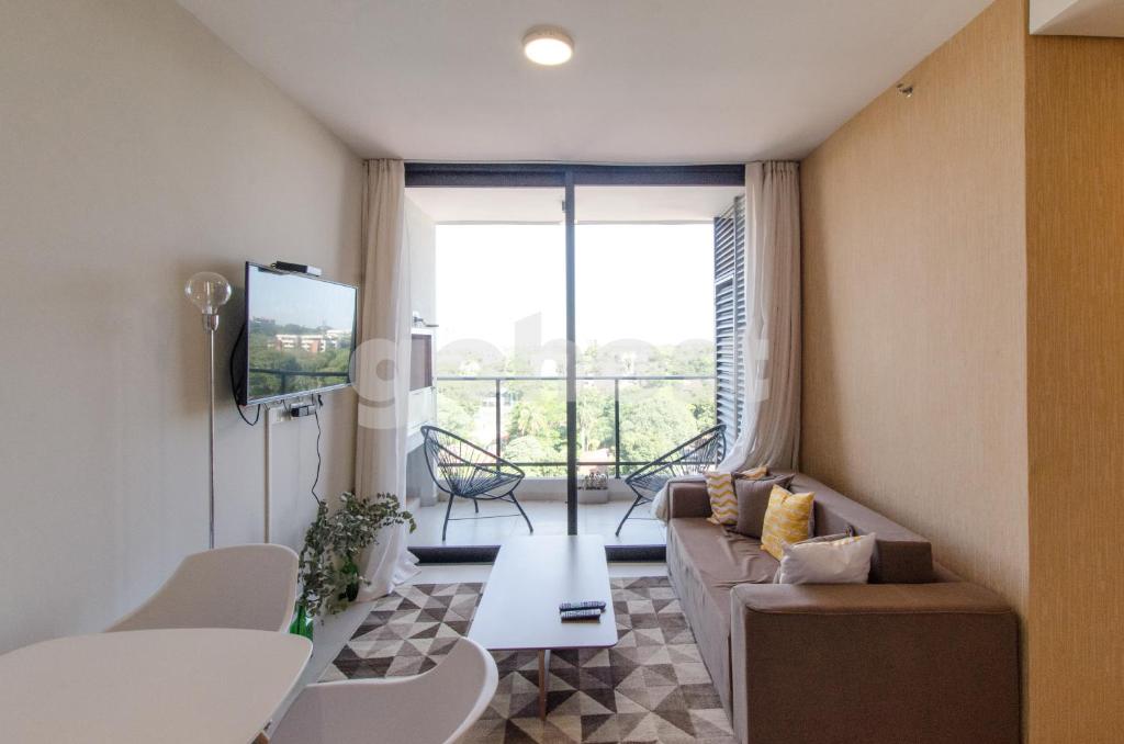 sala de estar con sofá y TV en Luxurious And Dazzling Villa Morra Apartment, en Asunción