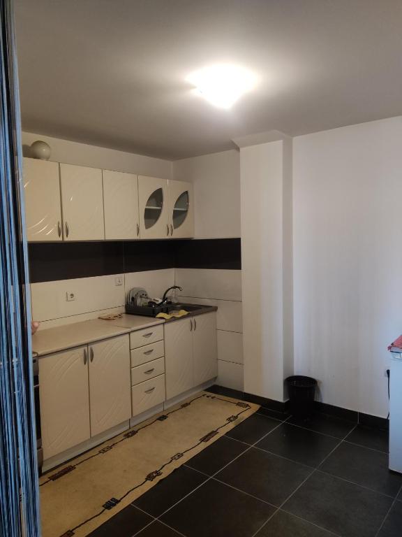una cocina con armarios blancos y una pared en blanco y negro en Kralj en Prokuplje