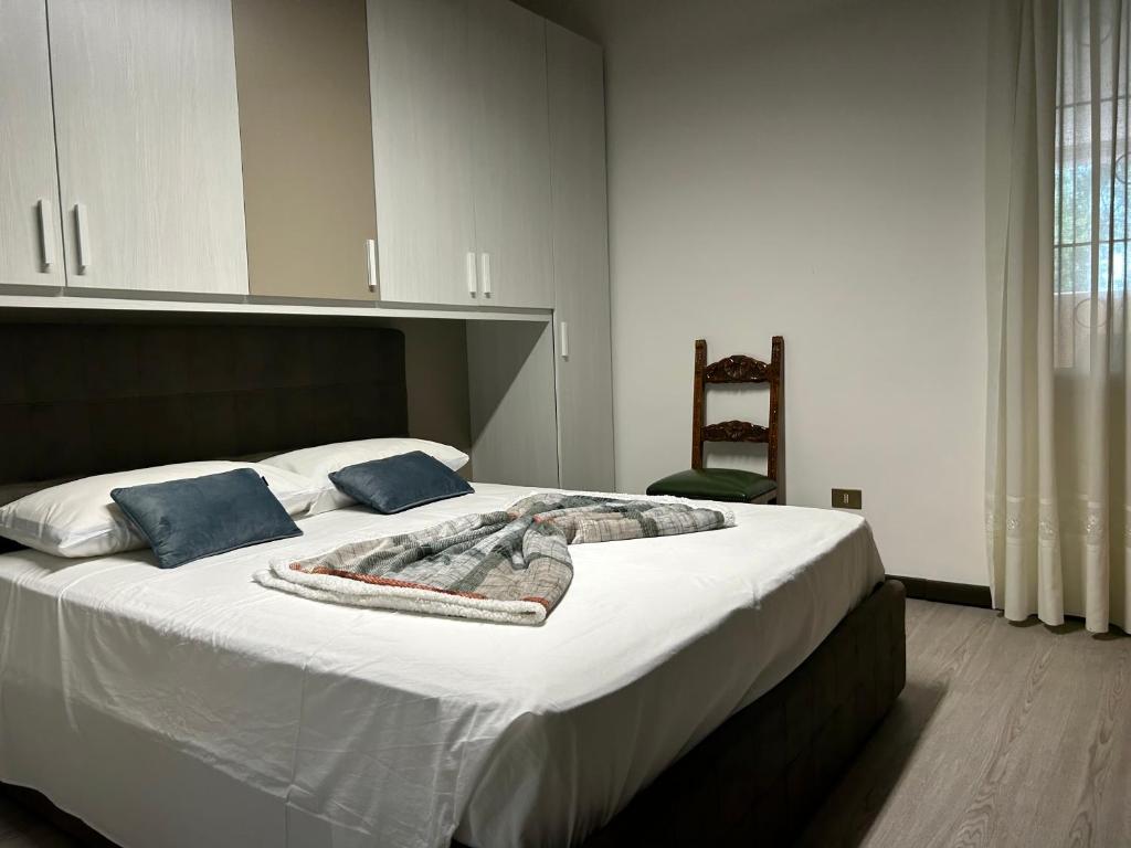 1 dormitorio con 1 cama grande con sábanas blancas y almohadas azules en Larocca Tourist Home 3, en Bassano del Grappa