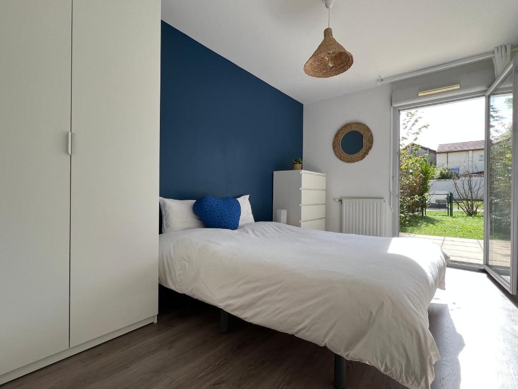 Un dormitorio con una cama con una pared de acento azul en Le Jardin de l'Arena - T3 Design - jardin privé - Garage sur demande - Proche Eurexpo, Groupama Stadium, LDLC Arena, en Décines-Charpieu